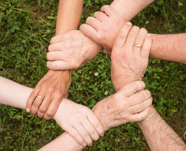 Image of people in social work joining hands to symbolize support for one another